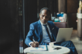 Businessman with laptop sitting at cafe writing