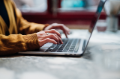 Side view of female hands typing on laptop keyboard