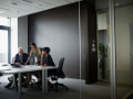Group of coworkers in discussion in glass walled office conference room businesswoman working on digital table