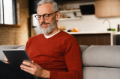 Closeup portrait of seated smiling middle-aged man using digital tablet.