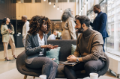 Businesswoman planning strategies with male coworker while sitting on couch in convention center.