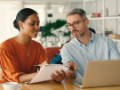 diverse multi-generational business people with paper and laptop discussing a project 