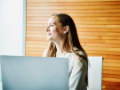 side view of smiling businesswoman working on laptop in office