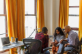 Multi-generational male and female business colleagues meeting with tablet sitting in office