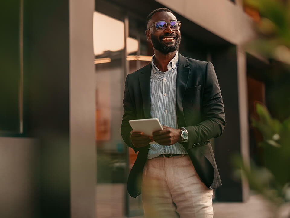 casually dressed young business man walking outside, tablet in hand