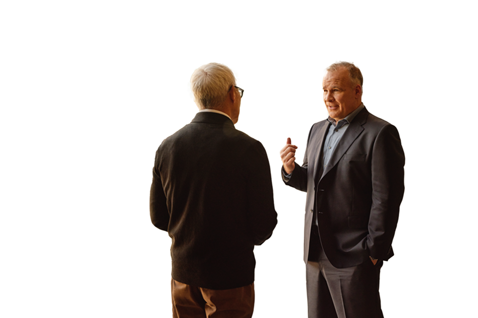 two business men standing and talking in office hallway with glass windows, angled bracket animation floating to right